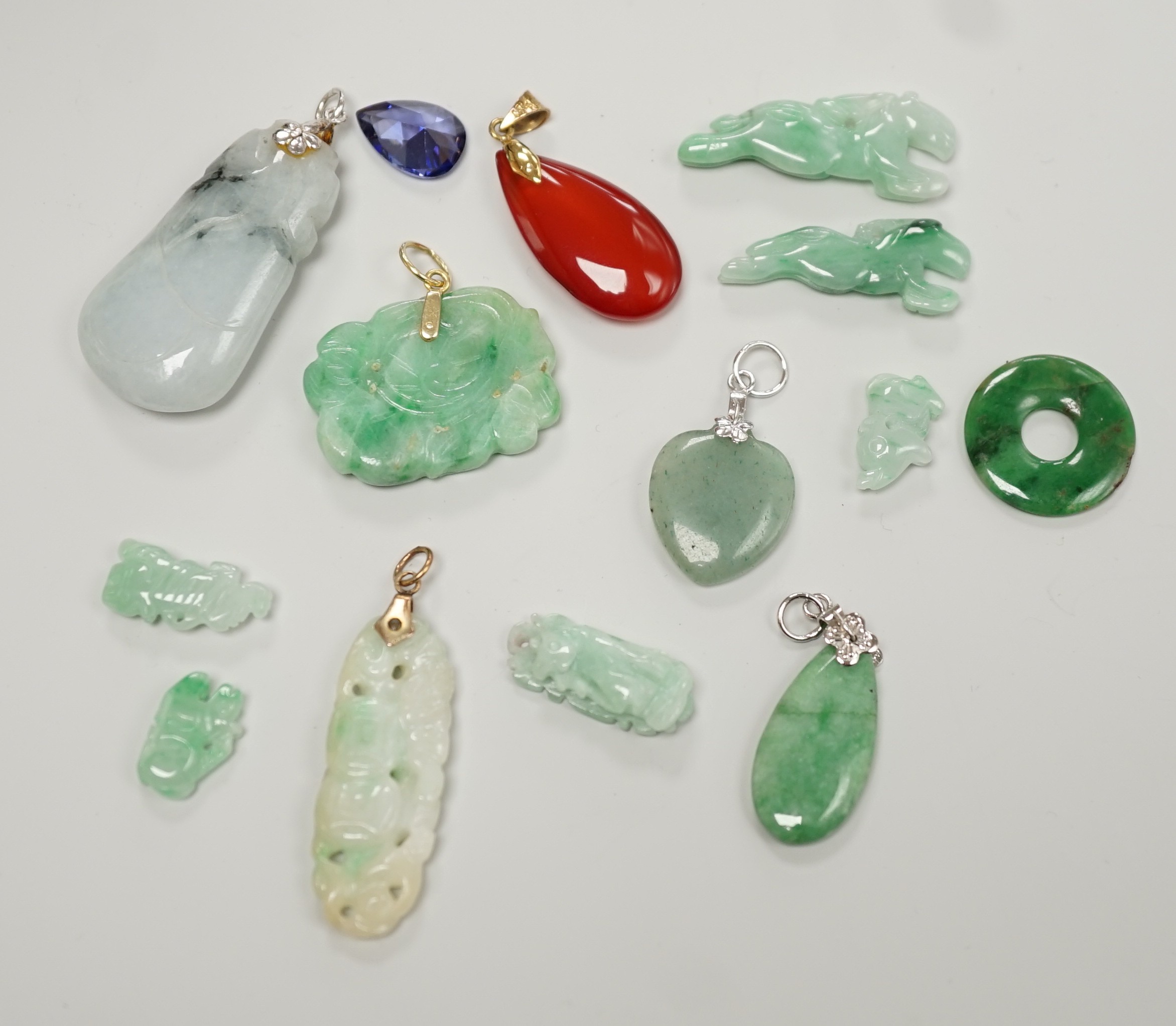 Twelve assorted carved jadeite items including five pendants, largest 40mm, a 14k mounted carnelian pendant and an unmounted pear cut simulated Tanzanite.